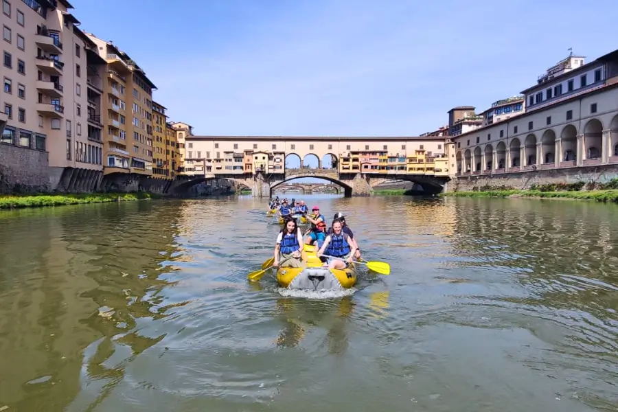 A group of people raft along the Arno River in Florence during a Team Building Urban Hiking experience organized by WeHike