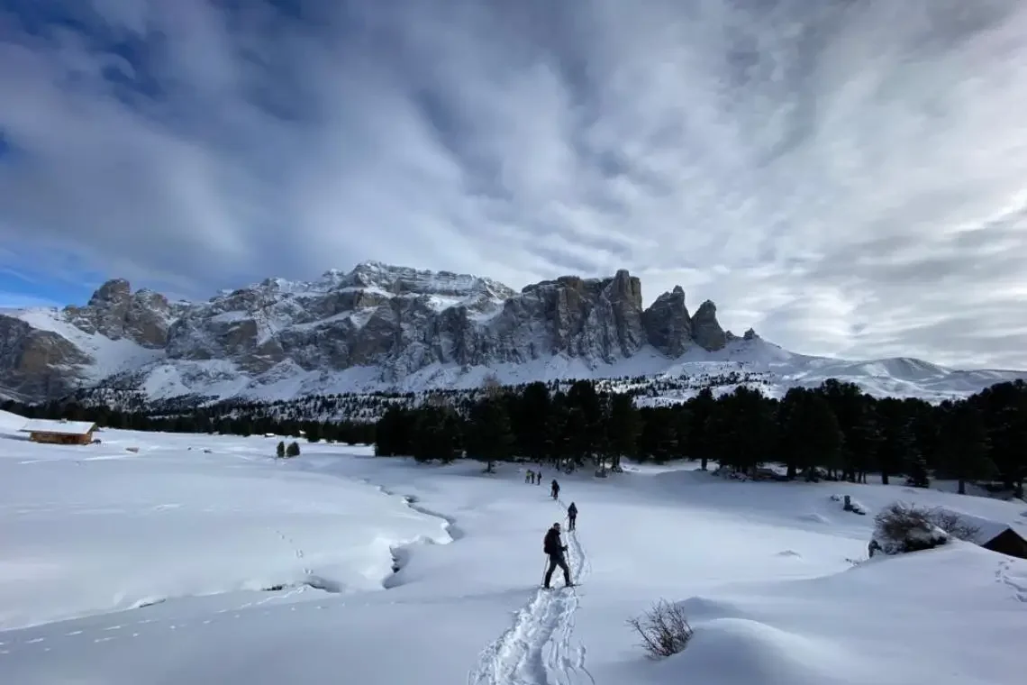 Escursionisti con le ciaspole camminano sulla neve tra le Dolomiti innevate durante un trekking invernale con WeHike